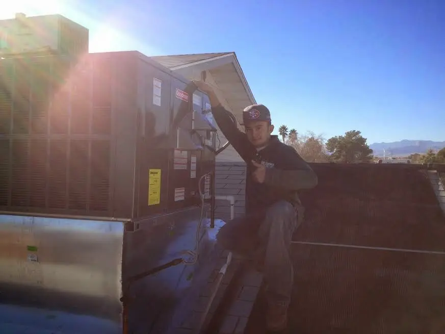 HVAC technician performing Air Duct Cleaning on a rooftop unit in Diboll
